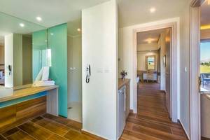 Badezimmer im Sandy Beach Hotel auf Kos mit blauen Glaswänden und Holzboden.
