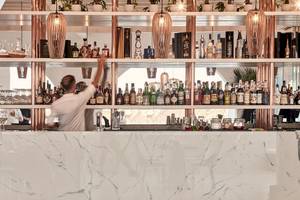 Ein Barkeeper steht im Cocktailbereich der Katikies Villas Mykonos und serviert Getränke.