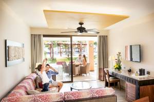 Suite-Wohnbereich im Barcelo Maya Beach mit offenem Balkon und Gartenblick.