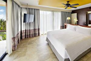 Hotelzimmer im Barcelo Maya Beach mit großem Bett, Fernseher und Fenstern.
