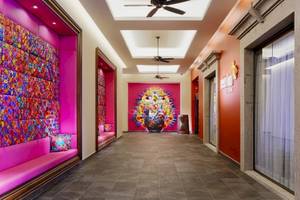 Der Innenbereich des Barcelo Maya Beach Hotels mit rosa Wänden, bunten Wandverkleidungen und einer zentralen Wandkunst.