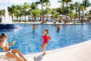Familie am Pool des Barcelo Maya Beach Hotel, mit einer Frau und zwei Kindern.