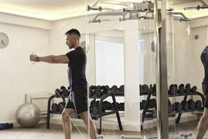 Mann trainiert in einem Fitnessstudio der Katikies Villas Mykonos mit einem Kabelzuggerät.