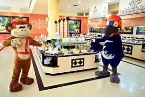 Zwei Maskottchen, ein Affe und ein Vogel, stehen vor einem Buffet im Bahia Principe Grand Coba Hotel.