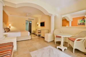 Hotelzimmer im Bahia Principe Grand Coba mit Bett, Schreibtisch, Spiegel und Korbstühlen.