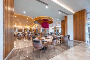 Innenbereich des Lago Hotels Restaurant mit Holzwänden und Marmorboden, vielen Tischen und Stühlen.