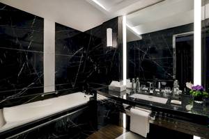 Schwarzes Marmorbadezimmer im Marriott Resort Palm Jumeirah, Dubai, mit Badewanne, Waschbecken und Spiegel.