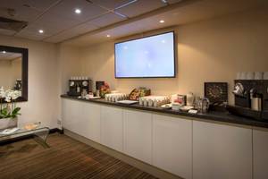 Frühstücksraum im Tower Hotel, London mit Fernseher, Kaffeemaschine und Frühstücksauswahl.