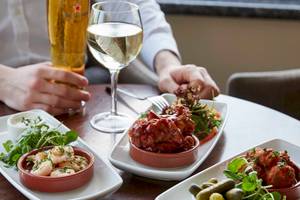 Ein Tisch im Tower Hotel, London, mit verschiedenen Gerichten und Getränken wie Wein und Bier.