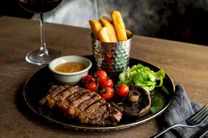 Ein Steak-Platter mit Beilagen und Salat auf einem schwarzen Teller im Tower Hotel, London.