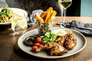 Ein Tisch im Tower Hotel in London mit einem Teller gebratenem Hähnchen, Pommes, Tomaten und Salat.