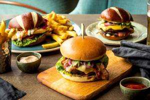 Zwei Burger mit Pommes und Beilagen auf einem Tisch im Tower Hotel, London.