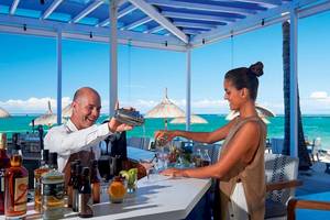 Ein Barmitarbeiter im Constance Ephelia Mahe Seychelles bereitet einen Cocktail zu.