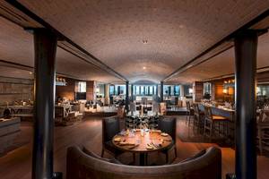 Innenansicht des Restaurants im Constance Ephelia Mahe Seychelles mit Holzboden und hohen Säulen.