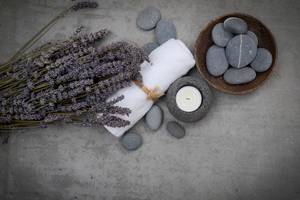 Lavendel, Handtuch, Kerze und Steine auf Beton