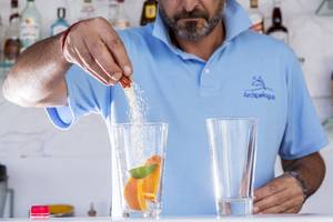 Mitarbeiter des Archipelagos Hotels fügt Zutaten in ein Glas für einen Cocktail hinzu.