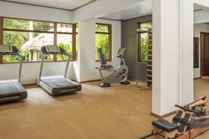 Fitnesszentrum im Anantara Maia Seychelles Villas mit Laufbändern, Rudergeräten und einer großen blauen Kugel.