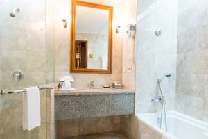 Badezimmer im Century Park Hotel mit einer Dusche, Badewanne, Waschbecken und Spiegel.