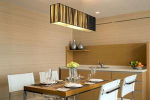 Speisezimmer im JC Kevin Sathorn Bangkok Hotel mit Tisch, Stühlen, Vasen und Früchten.
