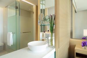 Badezimmer im AVANI+ Riverside Bangkok Hotel mit runden Waschbecken und Glasdusche.