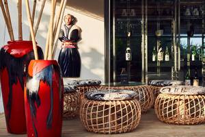 Hotellobby des Amari Havodda Maldives mit roten Vasen, Bambusstangen, Sitzhockern und einer Glasvitrine.