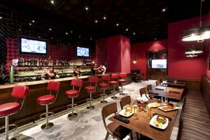 Innenbereich des Pullman Bangkok Hotel G mit roter Bar, Sitzstühlen und Essenstischen.