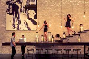 Innenbereich des Pullman Bangkok Hotel G mit Personen an einer Bar und einer Frau auf der Treppe.