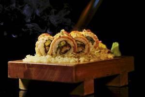 Sushi mit Raucheffekt auf einer Holzplatte serviert, mit Reis und Gemüse gefüllt