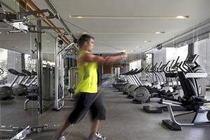 Fitnessstudio im SO/ Bangkok mit einem Mann, der Übungen mit einem Widerstandsband macht.