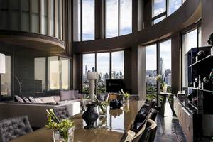 Innenansicht des Wohnbereichs im SO/ Bangkok Hotel mit großem Tisch und Panoramafenstern.