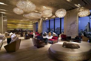 Innenansicht des SO/ Bangkok Hotel-Lounges mit großen Kronleuchtern, Möbeln und Blick auf die Stadt.