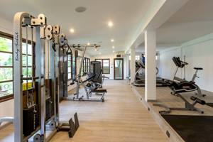 Fitness-Center im Sunwing Bangtao Beach Hotel mit Geräten und einem Mann, der auf einem Laufband läuft.