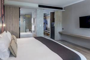 Schlafzimmer im La Flora Khao Lak Hotel mit Bett, Badezimmer und Fernseher