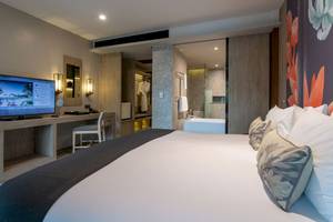 Innenansicht eines Hotelzimmers von La Flora Khao Lak mit Bett, Fernseher und Schreibtisch.