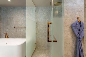 Badezimmer im La Flora Khao Lak Hotel mit Badewanne und Glasdusche.
