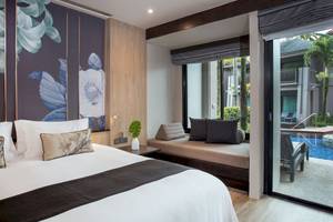 Schlafzimmer im La Flora Khao Lak Hotel mit Bett, Kissen und Pflanzendekor.