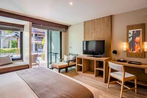 Innenansicht eines Zimmers im La Flora Khao Lak Hotel mit Bett, Fernseher und Schreibtisch.