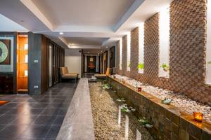 Eingangsbereich des La Flora Khao Lak Hotels mit Wasserlauf und Steinmauer.