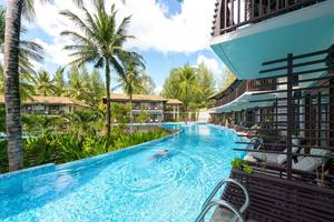 Schwimmbad im Haven Khao Lak Hotel mit Person und umgebenden Gebäuden.