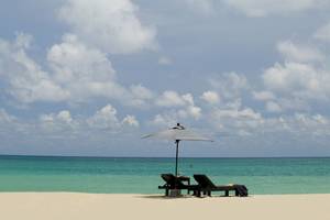 Ein Strand von Bangsak Village mit zwei Liegen und einem Schirm