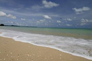 Foto einer Strandlinie mit sanften Wellen und blauem Himmel, bedeckt mit Wolken, vor dem Bangsak Village Hotel
