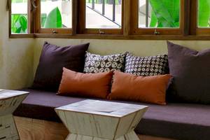 Sofa vor Fenster im Bangsak Village mit braunen und orangefarbenen Kissen.