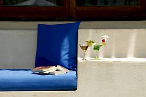 Sofa mit blauem Kissen und zwei Cocktails auf der Bank im Freien.