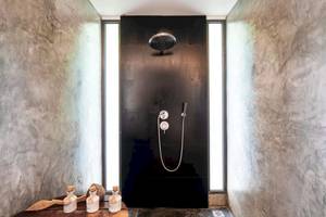 Dusche im TreeHouse Villas Koh Yao mit schwarzem Hintergrund und Marmorwänden.