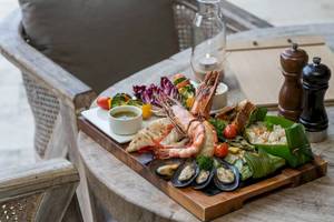 Fischplatte auf Holztisch bei TreeHouse Villas Koh Yao mit Garnelen, Muscheln und Gemüse.