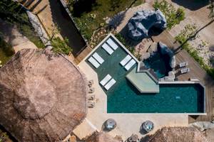 Luftaufnahme des Swimmingpools der TreeHouse Villas Koh Yao mit Sonnenliegen und Holzdeck.
