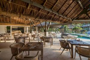 Innenansicht des Restaurants der TreeHouse Villas Koh Yao mit Tischen und Stühlen und Blick auf den Pool.