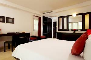 Schlafzimmer im Haadson Resort mit weißem Bett, rotem Kissen, Schreibtisch und Lampe.