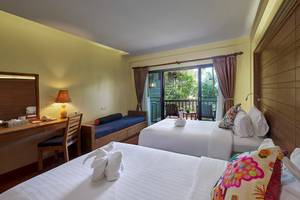 Innenansicht eines Zimmers im Khaolak Paradise Resort mit zwei Betten, Schreibtisch und Balkon.
