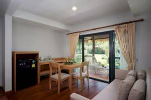 Innenansicht einer Suite im Khaolak Paradise Resort mit Esstisch, Minibar und Wohnbereich.